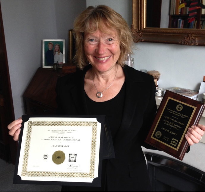 Anne Hornsby smiling from ear to ear, holding two of her awards