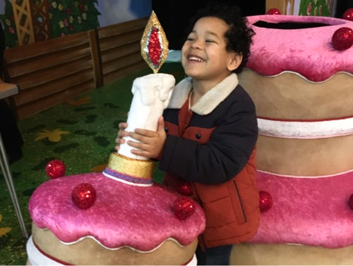 A little boy on a touch tour at The Grand, Wolverhampton, tries to blow out a giant candle on the top of a hat belonging to the Dame