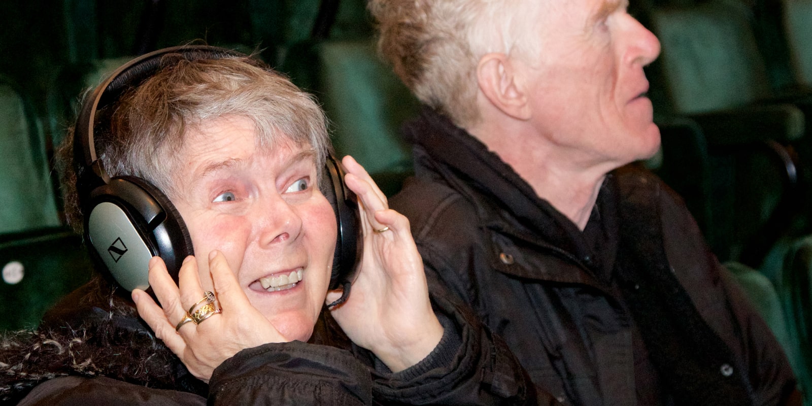 A listener tries on her headphones to hear the audio description at a performance at The Royal Exchange Theatre
