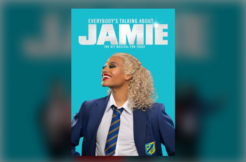 The image shows Jamie head and shoulders in school uniform, collar unbuttoned. He has smooth, brown skin, fully made up with red lips smiling, his heavily shadowed eyes closed, his head turned to the left. Long blonde ringlets cascade over his left shoulder. The strapline below the title reads The Hit Musical For Today.